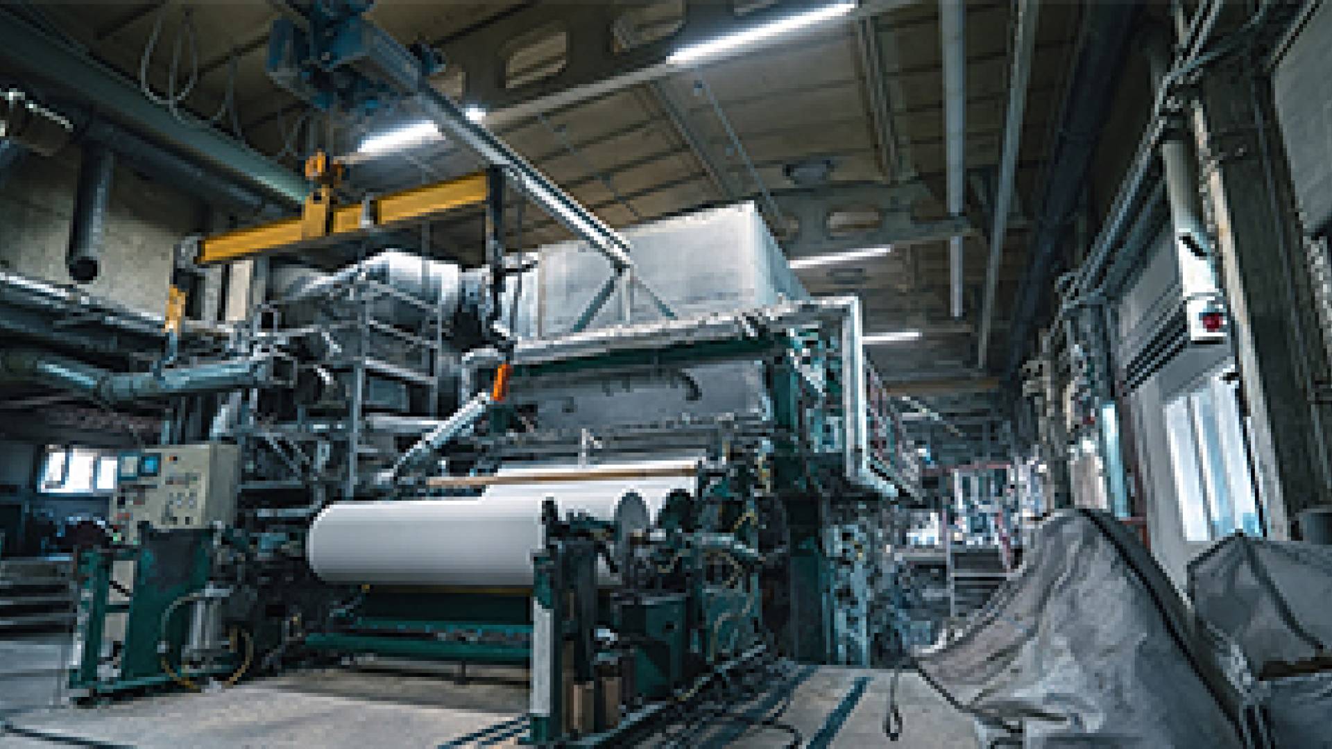 A production machine with rolls of new paper in a waste paper recycling factory.