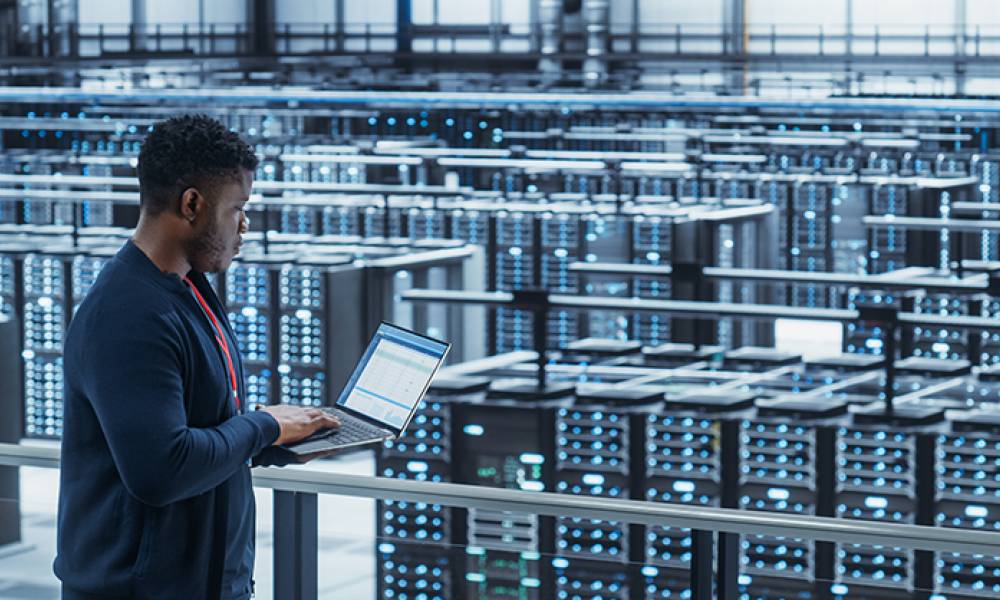 Data engineer using a laptop computer in a cloud computing facility.