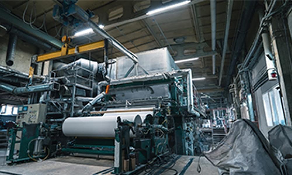 A production machine with rolls of new paper in a waste paper recycling factory.