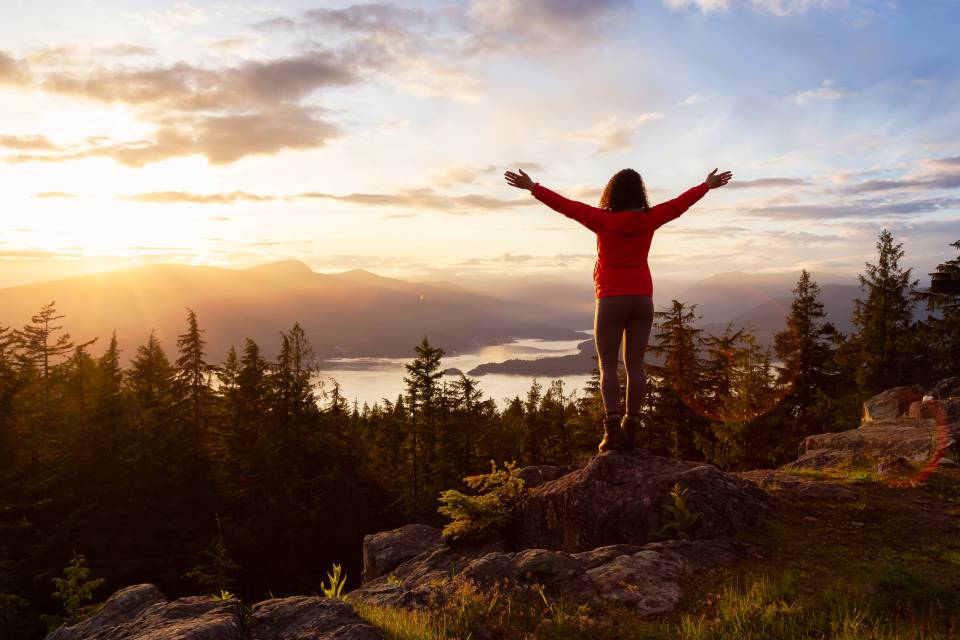 woman on top of a mountain enjoying the sunset view